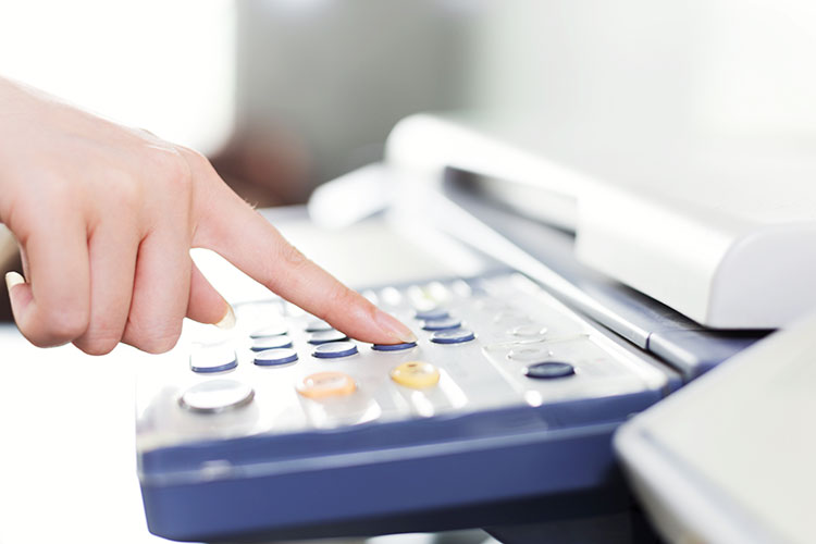 FAXを送信する女性の指先のアップ写真